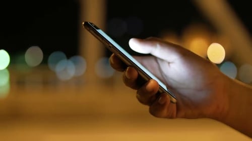 Hand Using Smartphone at Night, Urban Setting