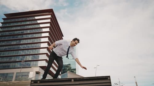 Flexible and cool businessman doing acrobatic tricks outdoor.