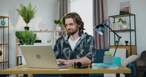 Guy which Sitting at His Workplace and Working on Laptop in contemporary home office