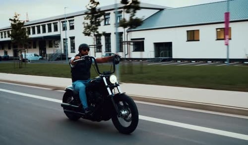 Man Rides Black Motorcycle on City Street
