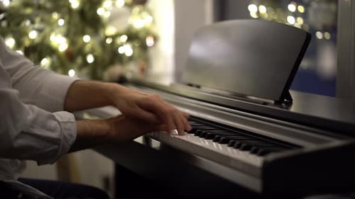 Un pianiste musicien joue du piano numérique à côté d'un sapin de Noël