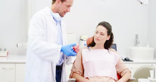 Dentist Explains Dental Model to Woman in Medical Office