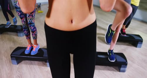 Women Doing Step Aerobics with Weights in Gym