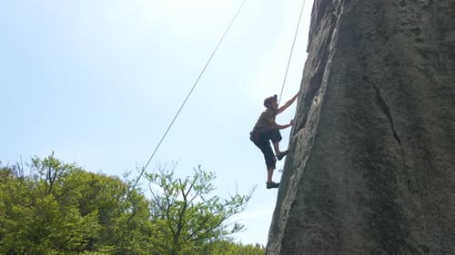 Strong Male Climber Climbing Steep Wall of Rocky Mountain