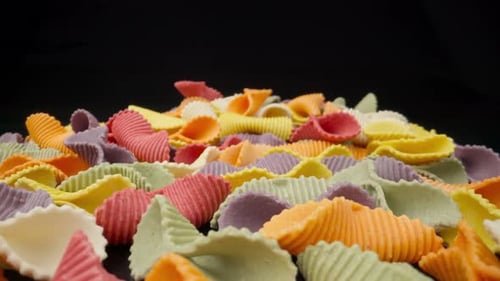 Creative Multicolored Pasta Farfalle on a Black Background in Perspective Background