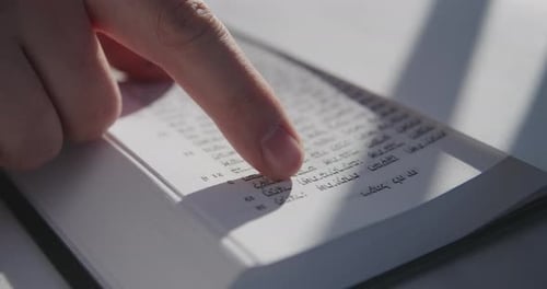 Finger Follows Hebrew Text in Open Book