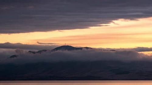 Time lapse of mountain surrounded by clouds during colorful sunset