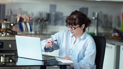 Woman Works at Laptop in Kitchen at Home