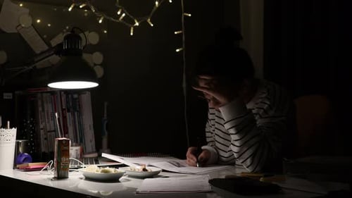 Student, der für die Prüfung am Schreibtisch studiert. Mit Computer und Lehrbüchern. Zeitraffer. Fokus auf Nahaufnahme.