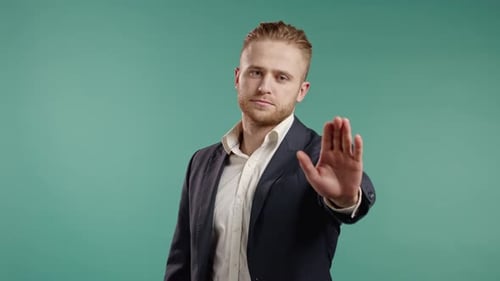 Man Signals Stop with Hand Against Teal Backdrop