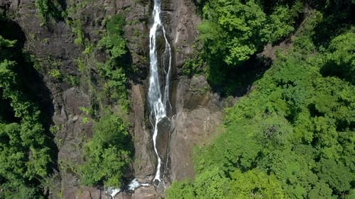 Aerial shot of a huge waterfall surrounded by trees in a forest in Costa Rica