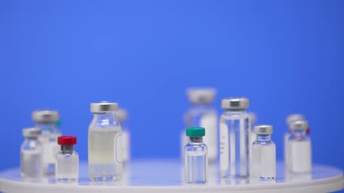 Coronavirus Vaccine in Ampoules Close Up on a Laboratory Table Blue Background