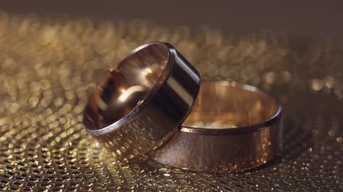 Wedding Gold Rings Lying on Shiny Glossy Surface. Shining with Light. Close-up