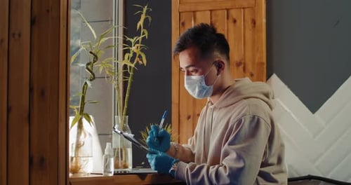 Young Adult Writes on Clipboard Wearing Protective Gear