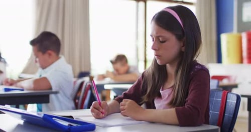 Focused Child Writing at School in Classroom