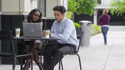 Two young business people sitting an meeting at outdoor cafe
