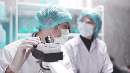 Young Adults Researching with Microscope in Laboratory