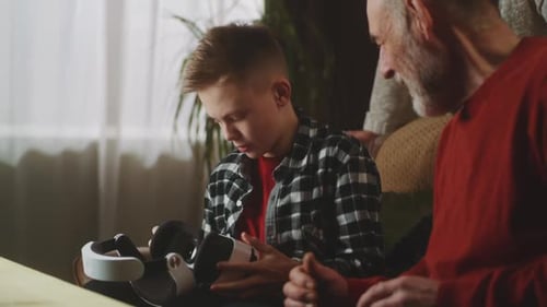 Boy Showing Virtual Reality Headset to Senior Man