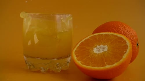Ice Cubes Dropped Into Orange Juice Glass