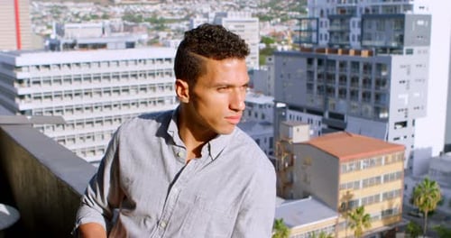 Man Drinks Coffee on City Rooftop on Sunny Day