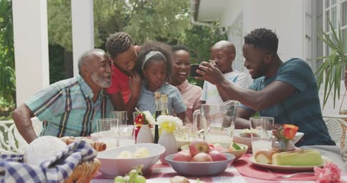 Family Gathers Around Table, Looking at Phone