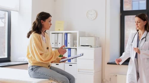 Female Patient Giving Papers to Doctor at Clinic