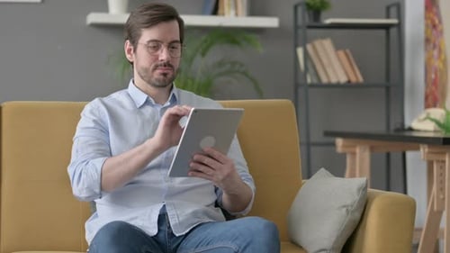 Man Using Tablet While Sitting on Couch