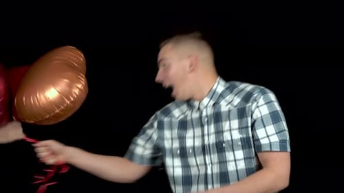 Smiling Man Holding Heart Balloons for Celebration