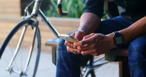 Person Using Phone Sitting Near Bicycle