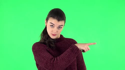 Frau spricht und zeigt mit dem Seitenfinger auf etwas, mit Kopierraum. Greenscreen