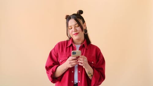 Woman Using Smartphone Against Solid Color Background