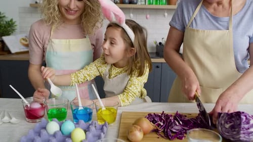 Aléjese de tres generaciones de mujeres que preparan huevos de Pascua. Fotografiado con cámara de helio RED 8K