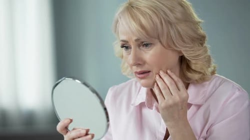 Mature Woman Examining Face in Mirror