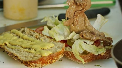 Close up of hands preparing roast beef sandwich