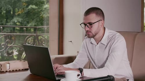 Young Adult Typing on Laptop in Office