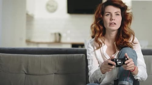 Verrückte Frau spielt Videospiel in der Küche zu Hause. Hübsches Mädchen hält Spielstation