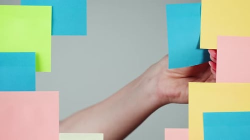 Hand Placing Bright Sticky Notes on Background
