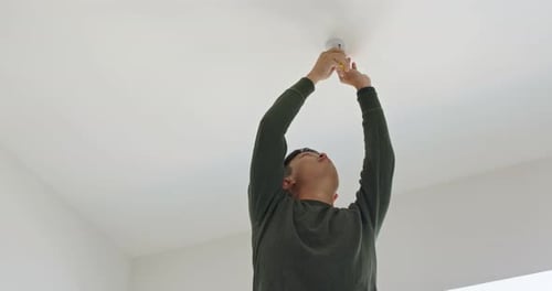 Man Installing New Lightbulb in Home