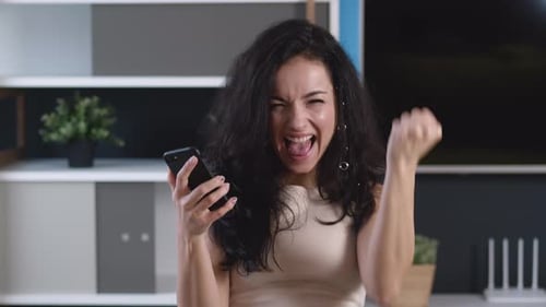 Woman Expressing Excitement While Using Her Mobile Phone