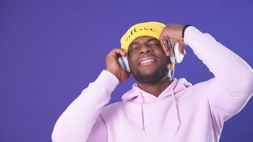 Cute African-American Man in Headphones Dressed in Street Style Wear, Listening To Music