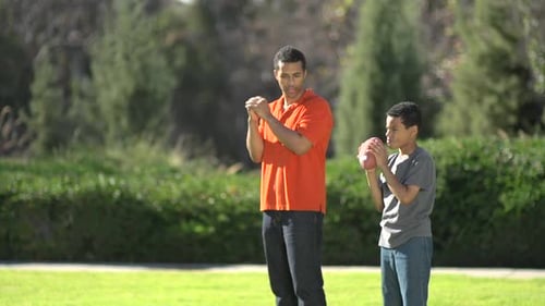 Adult and Child Practice Football Throwing in a Park