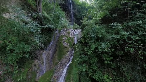 Scenic Waterfall Flows Through Lush Green Forest
