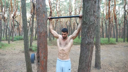Strong Man Showing Some Exercises on Horizontal Bar. Muscular Guy Doing Pull Ups. Athlete Performs