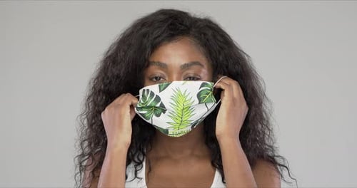 Cheerful Black Woman Putting on Cloth Mask