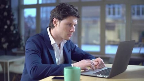 Young Adult Working on Laptop near Christmas Tree