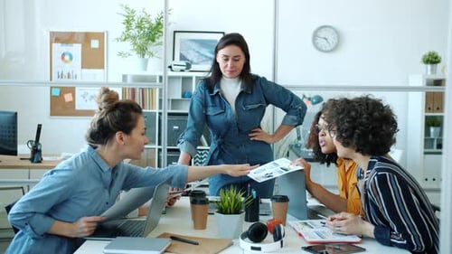 Diverse Group of Women Brainstorming Looking at Charts Discussing Business in Office