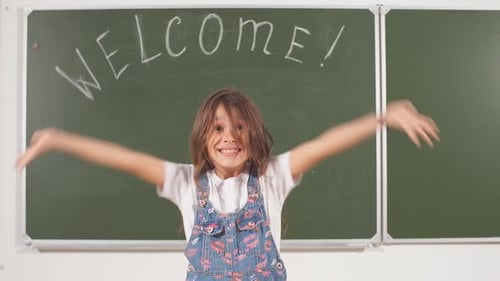 Excited Schoolgirl Welcomes in Classroom with Chalkboard