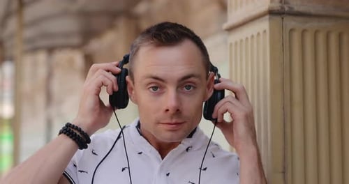 Man Puts on Big Headphones in a City