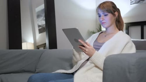 Woman Browsing Internet on Tablet PC, Sitting on Couch