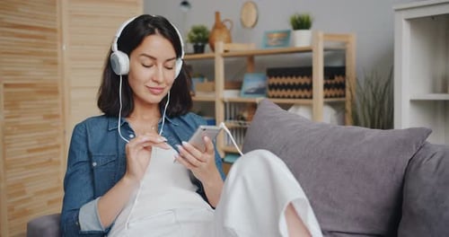 Schöne junge Frau hört Musik über Kopfhörer mit Smartphone
